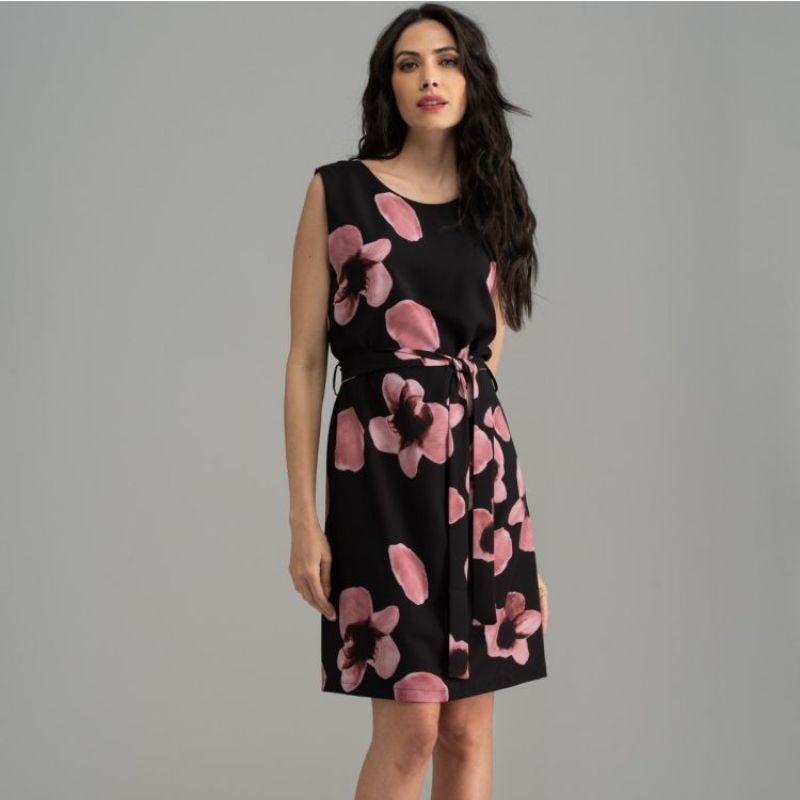 Donna che indossa un abito smanicato nero con fantasia a fiori rosa cipria